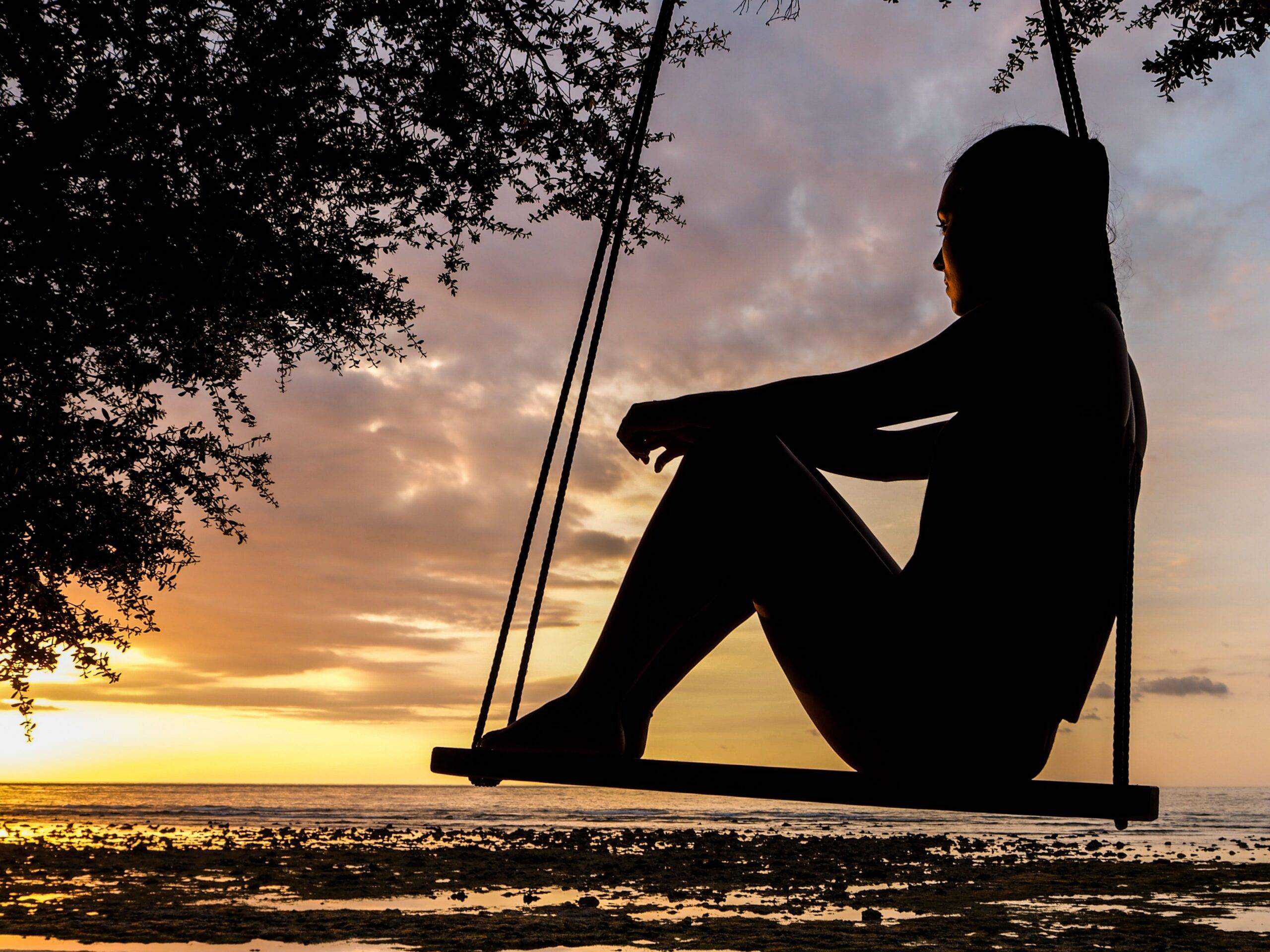 woman sitting on swing looking into the sunset